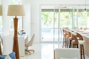 A modern dining area with a glass door leading to a balcony, white furniture, and a lamp. - Luxury New Grace Bay Villa/ private pool/2 min walk to reef, beach, restaurants (The Bight Settlement)