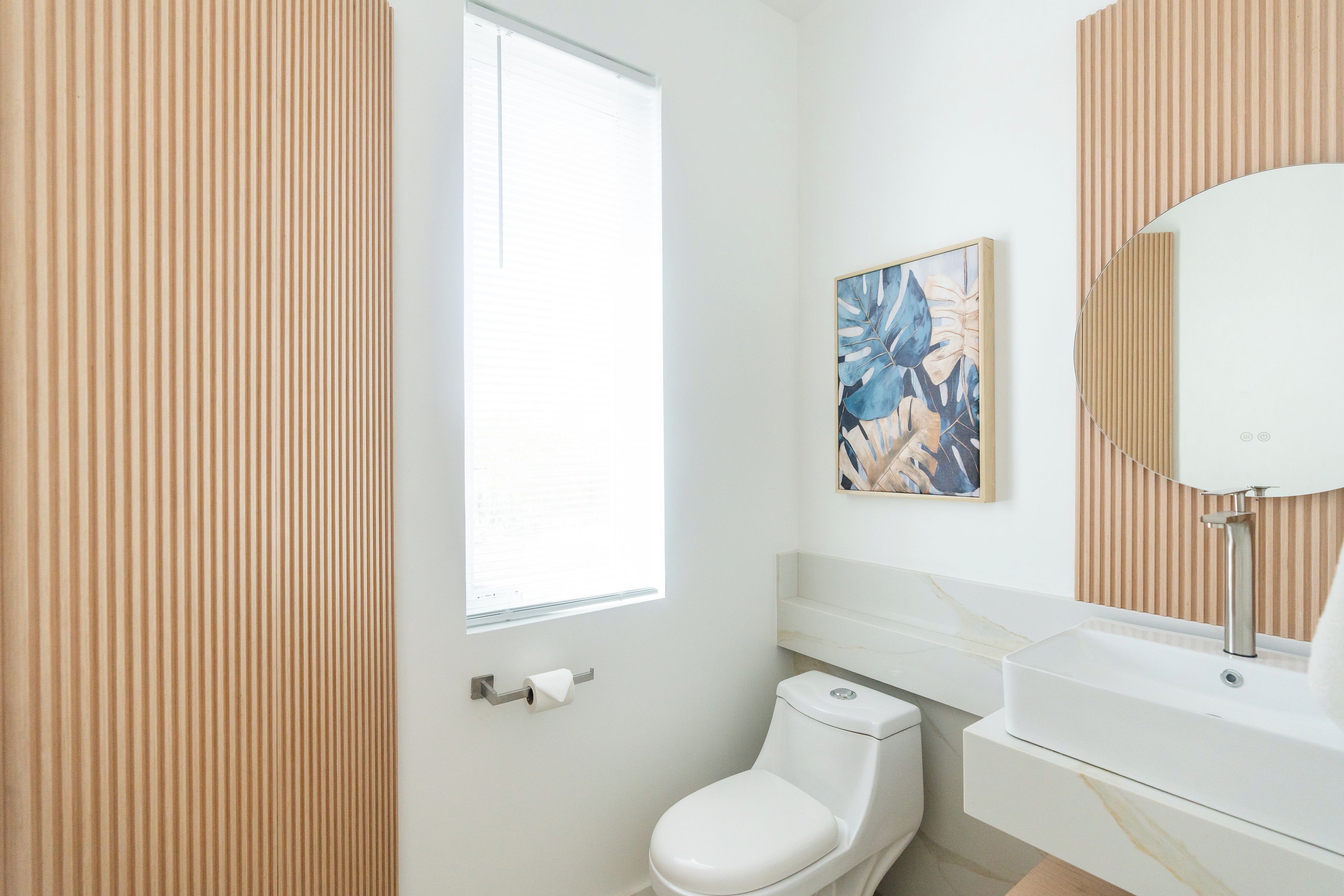 Ein modernes Badezimmer mit Toilette, Waschbecken und einem Fenster.