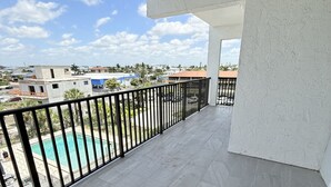 Ein Balkon mit Blick auf einen Swimmingpool und die umliegenden Gebäude.