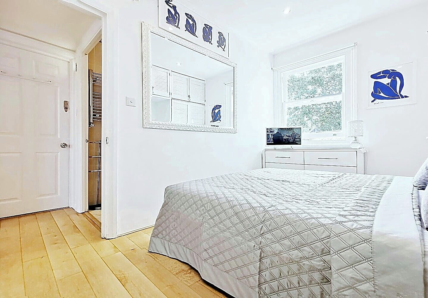A bedroom with a bed, a dresser, a mirror, and a window.
