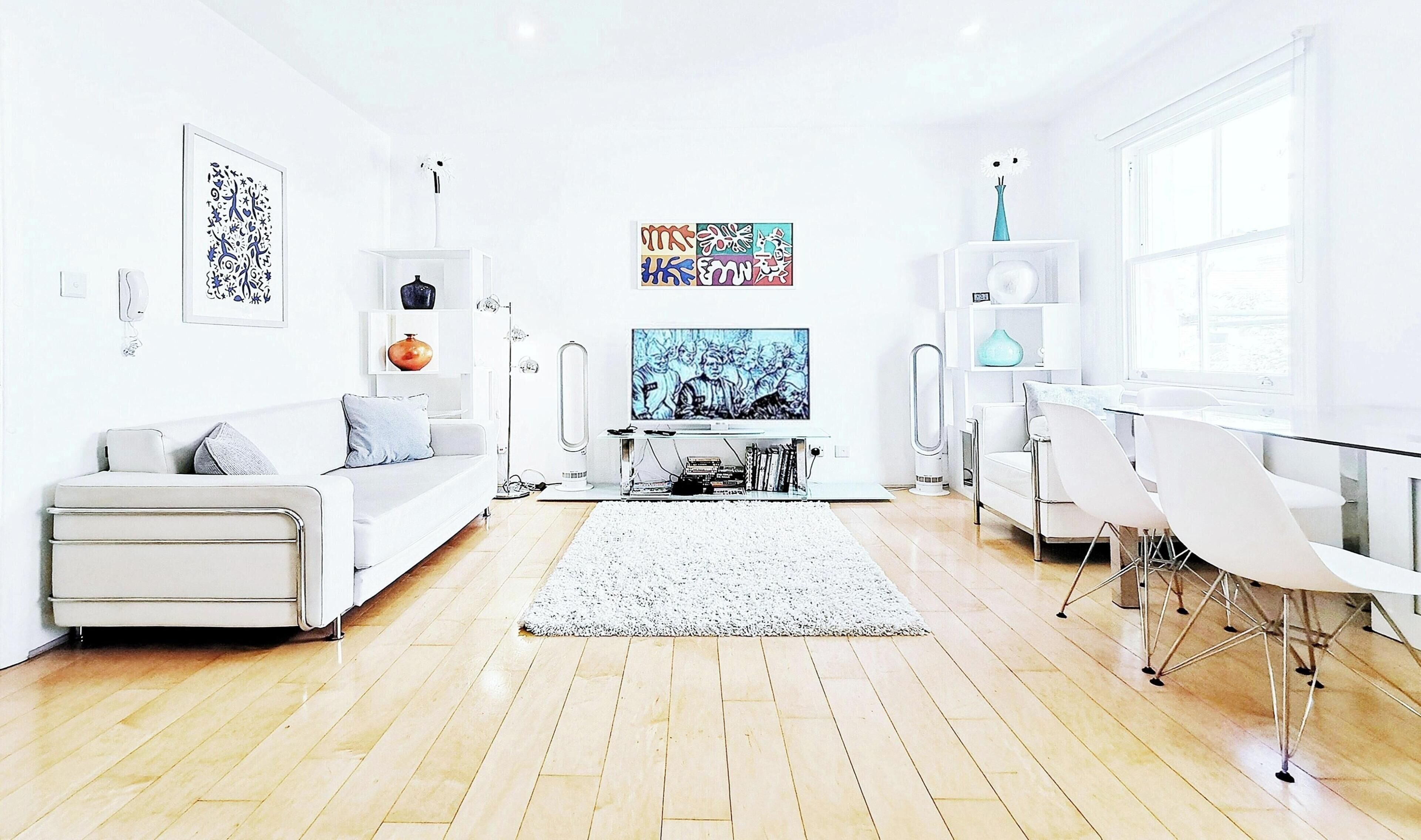 A modern living room with a sofa, TV, and dining area.