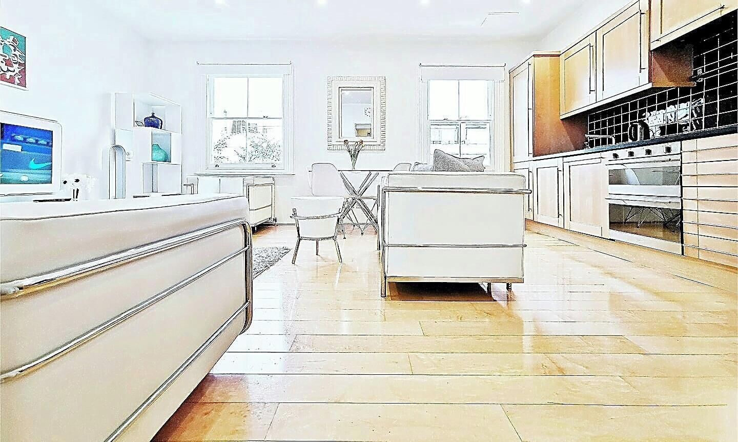 A modern kitchen with white cabinetry, a dining area with a table and chairs, and a view through the window.