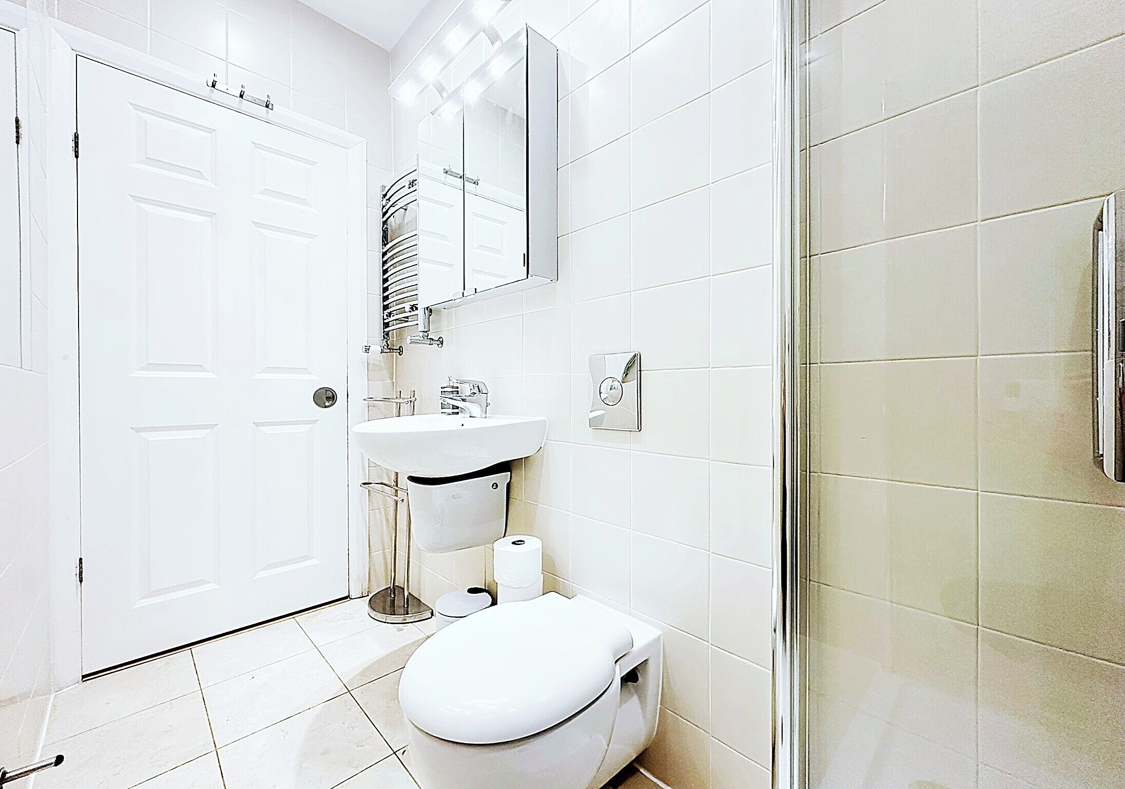 A bathroom with a toilet, sink, mirror, and shower area.