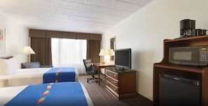 Ein Hotelzimmer mit zwei Betten, einem Schreibtisch, einem Fernseher, einer Mikrowelle und einer Kaffeemaschine.
