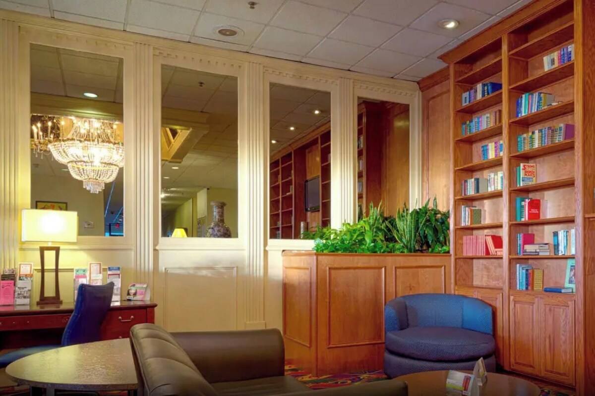 A hotel lobby with a seating area, a bookshelf, and a chandelier.