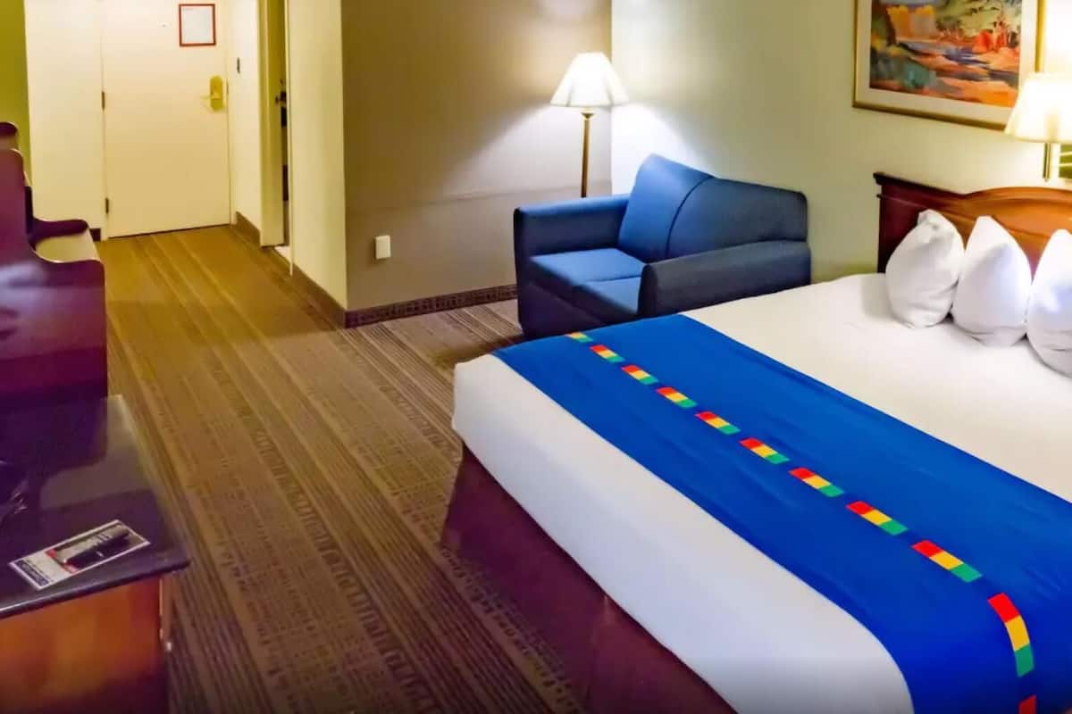 Ett hotellrum med en säng, en stol, ett skrivbord och en lampa.