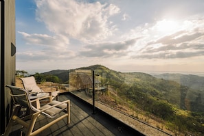 Ein Balkon mit Tisch und Stühlen mit Blick auf eine gebirgige Landschaft.