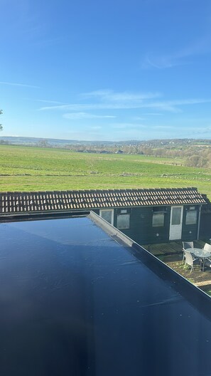 En tagterrasse med udsigt over et grønt område og fjerne bygninger.