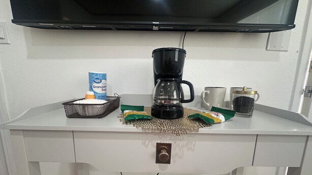 A kitchenette with a coffee maker, a basket, a carton of granulated sugar, and a packet of instant coffee. - Hotel Style 1-bedroom in lovely Orlando with AC (Orlando)