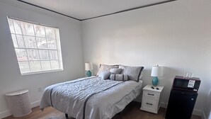 A bedroom with a bed, bedside tables, a lamp, a microwave, and a window with blinds. - Hotel Style 1-bedroom in lovely Orlando with AC (Orlando)