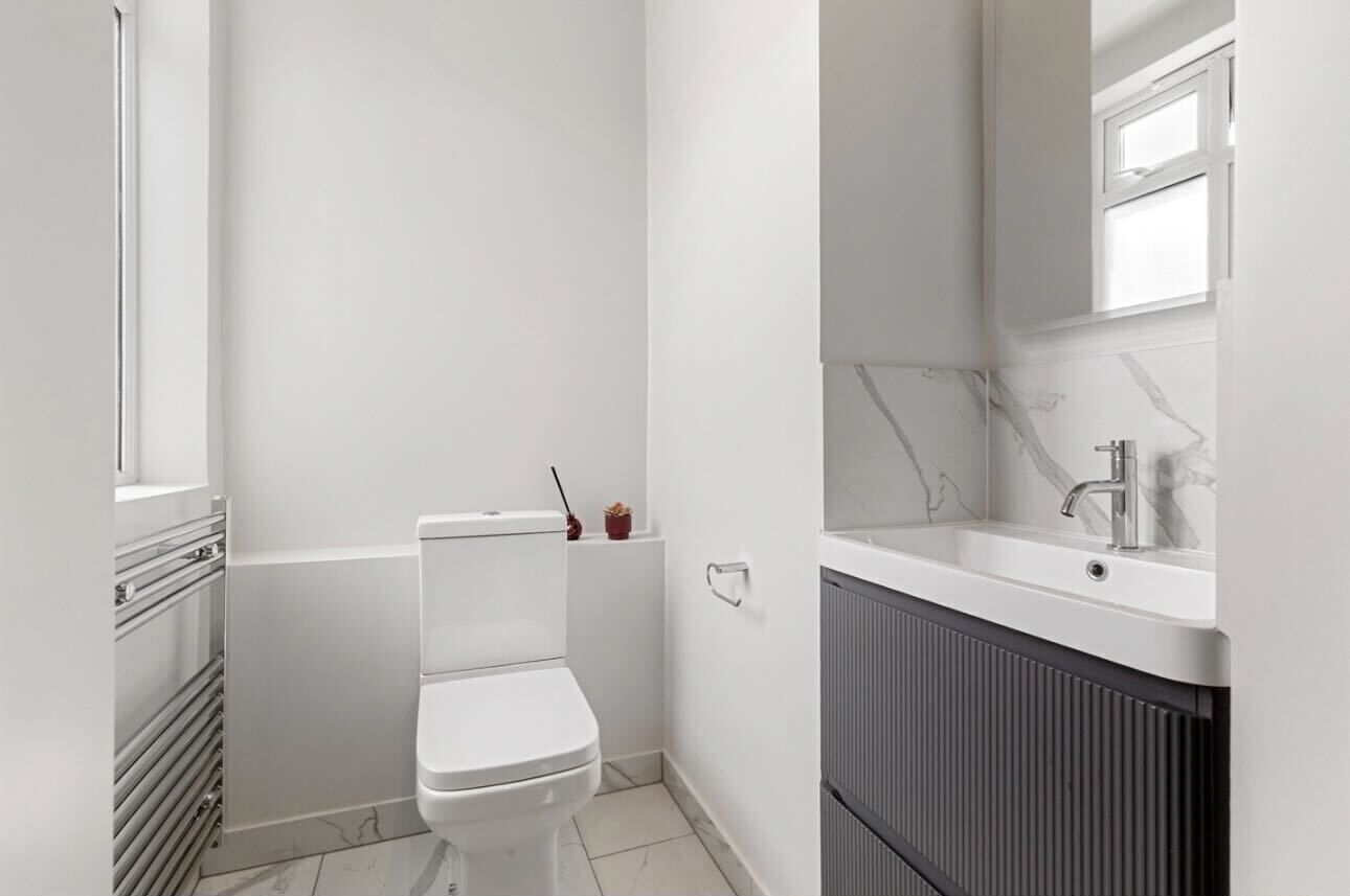 Une petite salle de bain moderne, équipée de toilettes, d’un lavabo et d’un miroir.