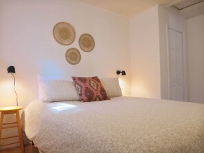 A bedroom with a bed, bedside lamps, and wall decorations.