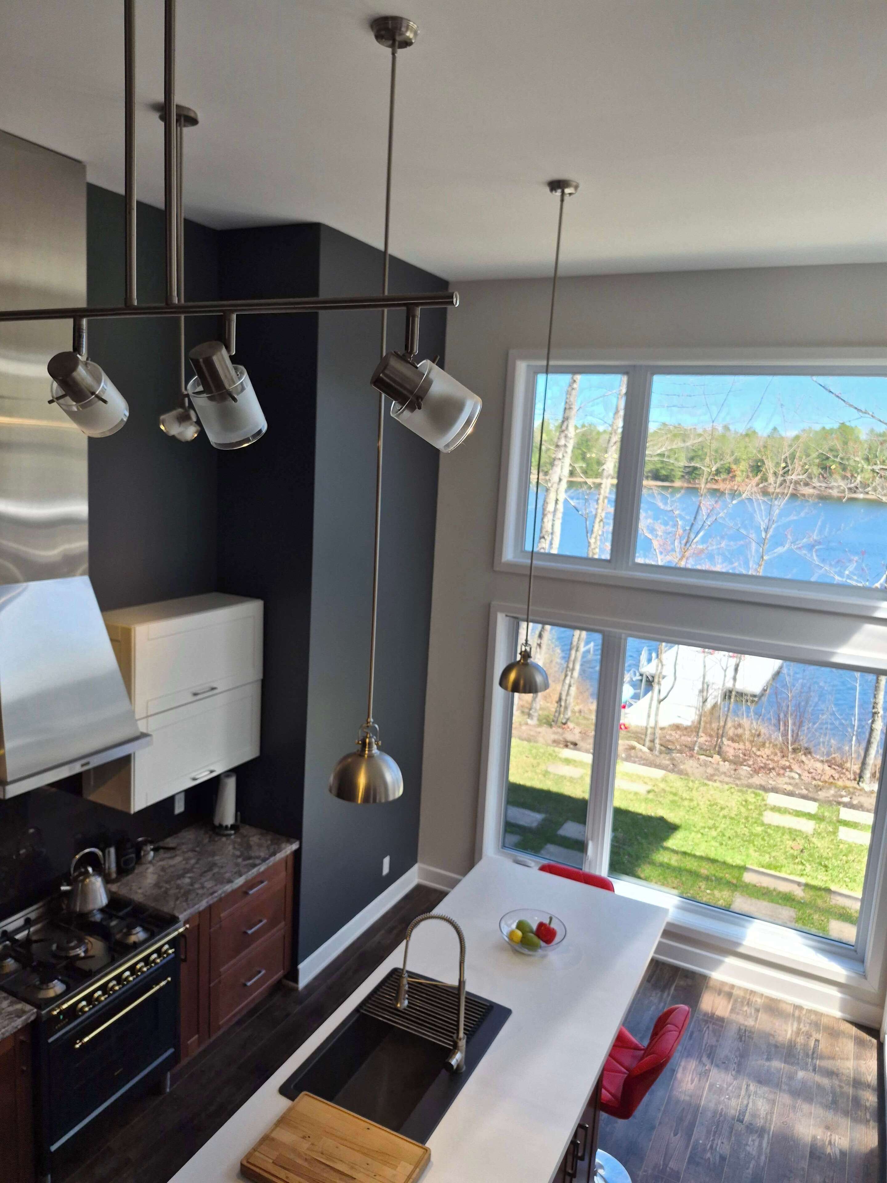 A modern kitchen with a large window, a built-in stove, and pendant lighting.