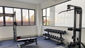 Een sportschool met gewichthefapparatuur, dumbbells en bankjes.