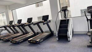 Een fitnessruimte met loopbanden, een stairmaster en een roeimachine.
