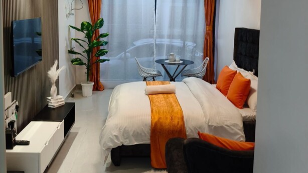 Een moderne hotelkamer met een bed, bureau, televisie, balkon met tafel en stoelen, en een kamerplant.
