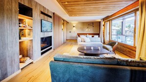 Een moderne woonkamer met een open haard, bank, salontafel en grote ramen.