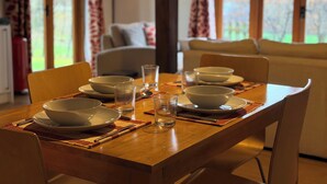 Une table à manger dressée avec des bols et des verres, un canapé en arrière-plan et une fenêtre avec des rideaux.