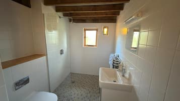 A bathroom with a toilet, a sink, a shower, and a window.