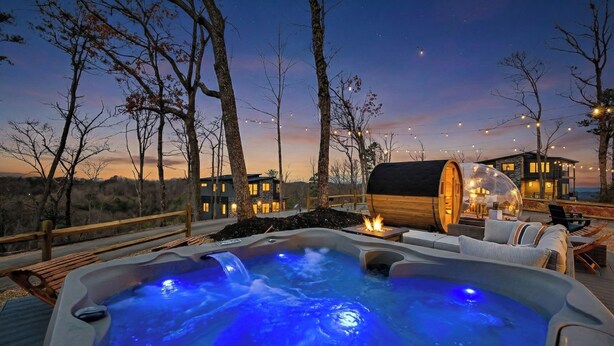 A hot tub with a waterfall feature, wooden deck, and outdoor seating area with a view of the mountains. - 2+m villa/NordicSpa/StargazingDome/Skylounge/Epic view/Pool/minigolf/Microevents (Sevierville)