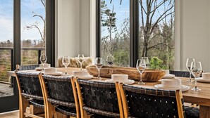 A dining area with a wooden table, black woven chairs, and large windows with a view of trees. - 2+m villa/NordicSpa/StargazingDome/Skylounge/Epic view/Pool/minigolf/Microevents (Sevierville)