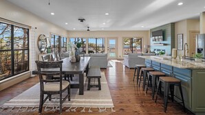 Una cocina amplia con una isla grande, un comedor con mesa y sillas de madera, y un ventilador de techo.
