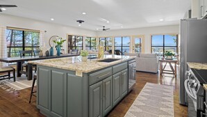 Una cocina moderna con una isla grande, suelo de madera y ventanas amplias que ofrecen vistas al exterior.
