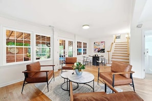 A spacious living room with leather chairs, a round coffee table, and large windows.