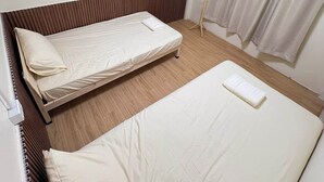 Huoneessa on kaksi sänkyä, peili, ikkuna, jossa on verhot, ja ilmastointilaite.