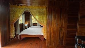 Una habitación de madera con una cama, una mesita de noche y un armario.