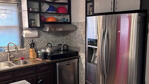 Cucina con frigorifero in acciaio inox, lavastoviglie e pannelli backsplash piastrellati.