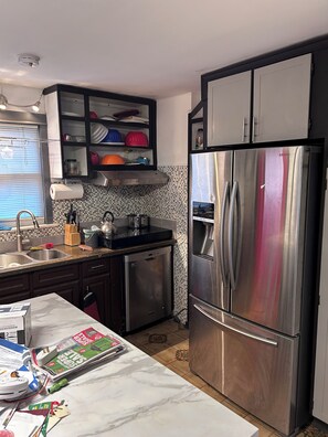 A kitchen with a stainless steel refrigerator, a dishwasher, and a tiled backsplash.