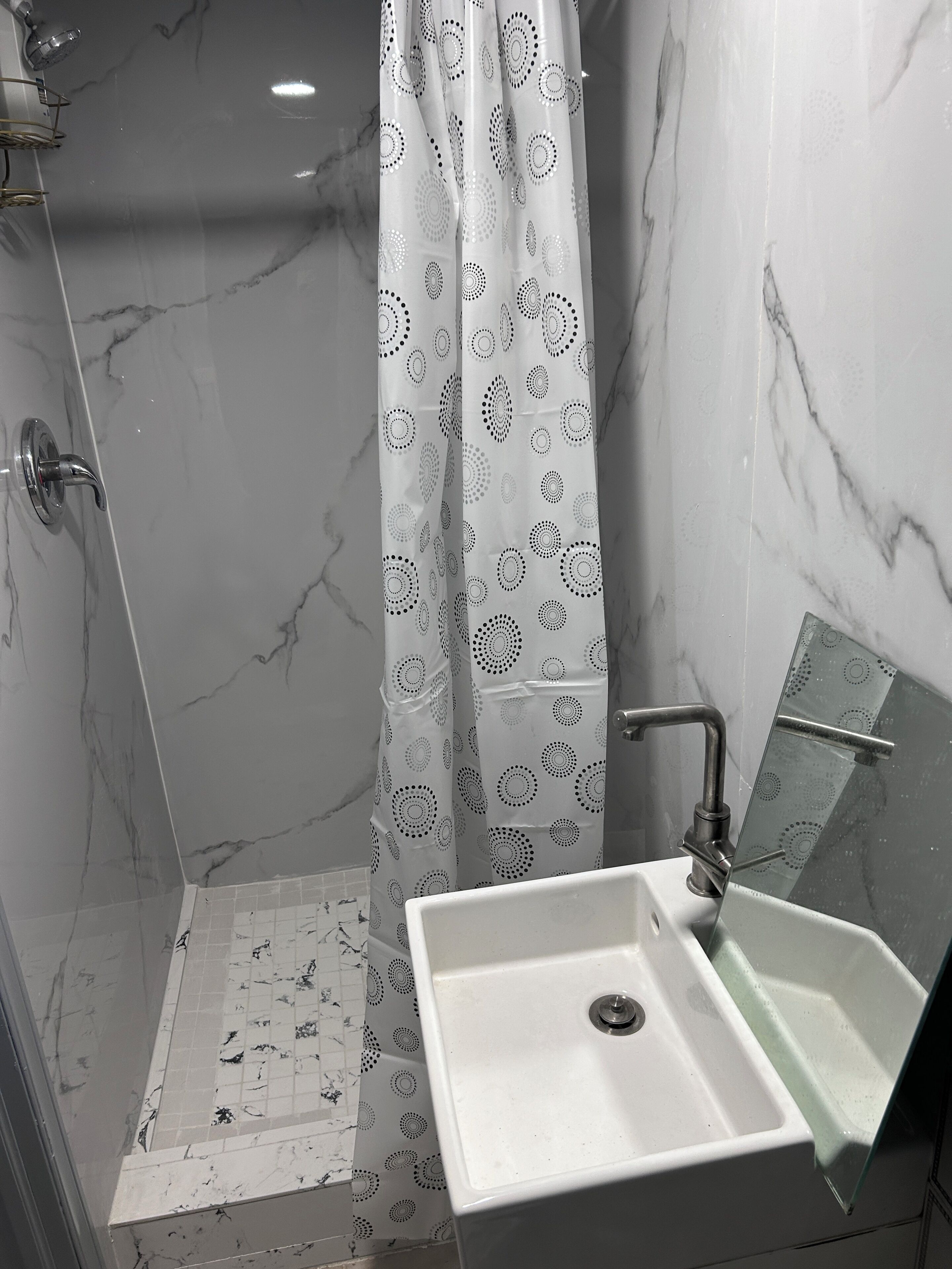 A bathroom with a shower, a sink, and a mirror.