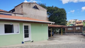 Un edifici amb façana verda, teulada enrajolada i un pati pavimentat.