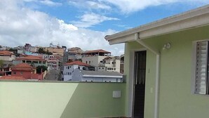 Edifici amb un pati enrajolat, una porta i vistes a una zona residencial amb cases.