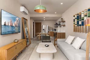 A modern living room with a dining area, kitchen, and a large flat-screen TV. - Las Arenas de Cabo one block from the beach (Cabo San Lucas)