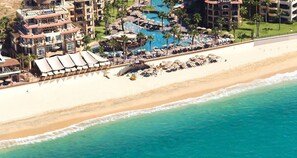 An aerial view of a beachfront hotel with multiple swimming pools, beach umbrellas, and a sandy beach. - Lux 1BR Elite Suite at Villa del Arco Beach Resort & Spa, Medano Beach Sleeps 4 (Cabo San Lucas)