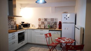 A compact kitchen with white cabinets, a microwave, a coffee maker, and a red refrigerator. - Port House (Bourg)