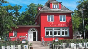 Un edificio rojo con un letrero que dice 'Sechhaus MIEBESORF' y una cerca blanca de piquetes al frente.
