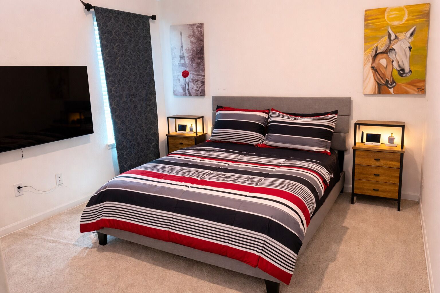 Een slaapkamer met een bed, twee nachtkastjes, een televisie en kunst aan de wanden.