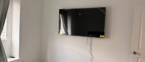 A bedroom with a bed, a wall-mounted TV, and a door.