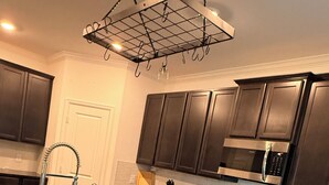 Une cuisine moderne avec des meubles de couleur sombre, une hotte de cuisine en acier inoxydable, un four encastré et un plan de travail en granit.