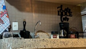 Una cucina con piastrelle a parete, una macchina da caffè, zucchero e caffè.