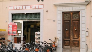 Ein Gebäude mit einem Schild, auf dem 'Cicli Rai' steht, und eine Reihe Fahrräder, die davor abgestellt sind.
