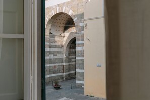 Un couloir voûté en pierre, avec un pot de fleurs à l’extrémité.