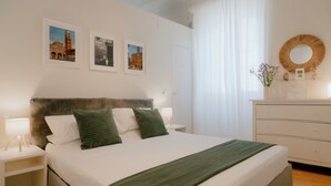 Ein ordentlich eingerichtetes Schlafzimmer mit einem Bett, Nachttischen, einer Kommode und Wandbildern.