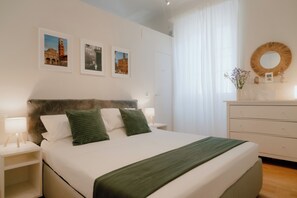A neatly arranged bedroom with a bed, bedside tables, a dresser, and wall-mounted artwork. - Stay in Lucca inside the Walls | A/C | WiFi | Historic Center (Lucca)