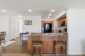 Eine Küche mit Holzschränken, einem schwarzen Kühlschrank und einer Marmarbeiteplatte.