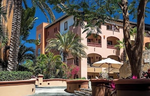 Ein Hotelinnenhof mit Palmen, einem Wasserspiel und einem Gebäude mit Balkonen.