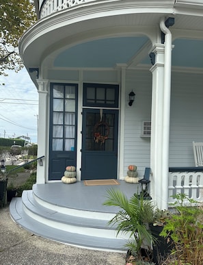 Ein Haus mit einer dunkelblauen Haustür, einer weißen Veranda und einem kleinen Garten mit Pflanzen.